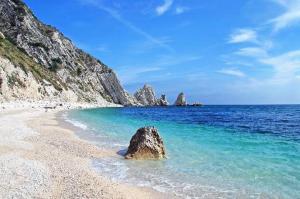 a rock sitting in the water on a beach at La Casa Bianca in Camerano