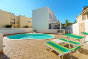 - une piscine avec 2 chaises longues et une maison dans l'établissement Residence Blu Mare, à San Vito Lo Capo
