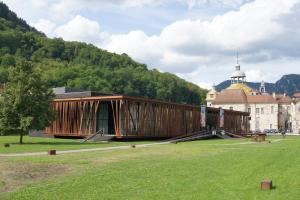 a wooden building in a field in front of a building at Au P'tit Grillon in Salins-les-Bains