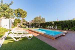 a swimming pool with two white chairs and a table and a pool at Kalacandi in Cunit
