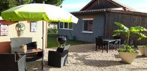 a patio with a green umbrella and chairs and a table at Le Cocon des Oiseaux in Lamonzie-Saint-Martin