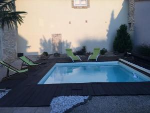 a swimming pool with green chairs next to a building at Le Nid de Cissé in Cissé