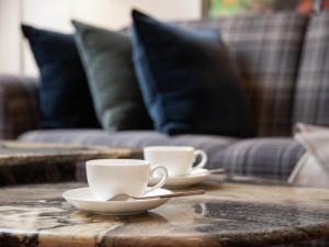 two coffee cups on a wooden table with a couch at Apartment Chalet Abendrot apARTments-19 by Interhome in Grindelwald