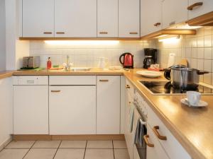 a kitchen with white cabinets and a stove top oven at Apartment Chalet Abendrot apARTments-25 by Interhome in Grindelwald
