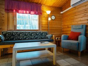 uma sala de estar com um sofá, uma cadeira e uma mesa em Holiday Home Aittoniemi ii by Interhome em Hopsu