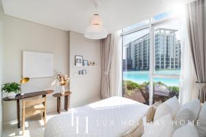 a bedroom with a bed and a desk and a window at LUX The District One Lagoon View Suite in Dubai