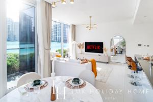a living room with white furniture and a large window at LUX The District One Lagoon View Suite in Dubai