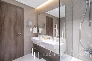 a bathroom with two sinks and a shower at LUX The District One Lagoon View Suite in Dubai