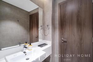 a bathroom with a white sink and a wooden door at LUX The District One Lagoon View Suite in Dubai