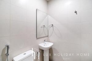 a white bathroom with a sink and a mirror at LUX The District One Lagoon View Suite in Dubai