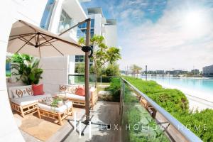a balcony with furniture and a view of the water at LUX The District One Lagoon View Suite in Dubai