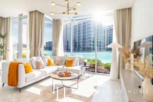 a living room with a white couch and a large window at LUX The District One Lagoon View Suite in Dubai