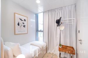 a white room with a bed and a window at LUX The District One Lagoon View Suite in Dubai