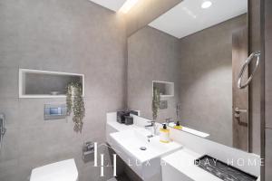 a bathroom with a white sink and a toilet at LUX The District One Lagoon View Suite in Dubai