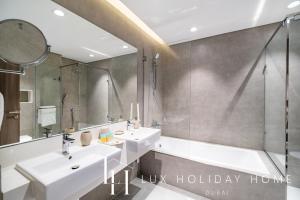 a bathroom with two sinks and a shower at LUX The District One Lagoon View Suite in Dubai +29 photos