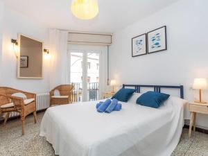 a bedroom with a large white bed with blue pillows at Apartment Gregal by Interhome in Tossa de Mar