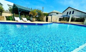 a large blue swimming pool with white chairs in it at Alella by the sea in Gnarabup