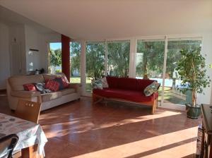un soggiorno con divano rosso e finestre di Chalet con gran jardin y piscina privada a Peñíscola