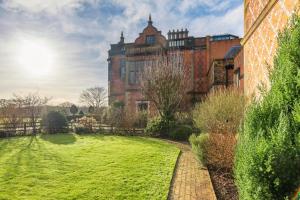 an old building with a grassy yard in front of it at East House in High Legh