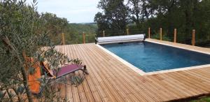 a swimming pool on a wooden deck next to at Le Refuge des libellules in Daglan