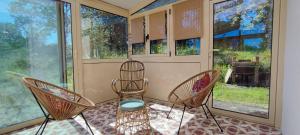 a screened in porch with two chairs and windows at Le Refuge des libellules in Daglan