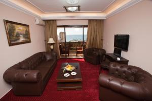 sala de estar con sofá de cuero y TV en Queens Land Hotel, en Jounieh