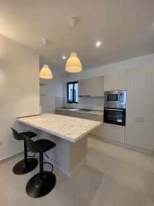 una cucina con bancone e 2 sgabelli da bar di Swieqi Malaika New Apt 3 a Is-Swieqi