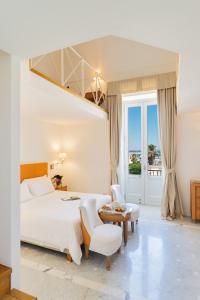 a bedroom with a large bed and a table and chairs at Palazzo del Corso – Boutique Hotel in Gallipoli