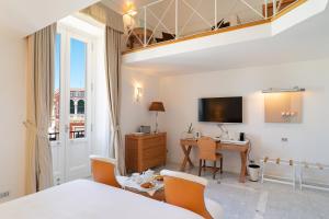 a bedroom with a bed and a desk and a television at Palazzo del Corso – Boutique Hotel in Gallipoli
