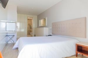 a bedroom with a large white bed and a table at Hotel Avenida in Póvoa de Varzim