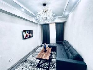un soggiorno con un divano e un lampadario di Smart City APARTMENT a Samarkand Altre 4 foto