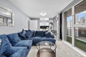 a living room with a blue couch and a glass table at 2-Bedroom Apartment Short Term Rental & Flexible Renting Canary Wharf in London