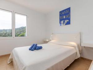 ein weißes Schlafzimmer mit einem Bett mit blauem Objekt darauf in der Unterkunft Holiday Home El Moli-1 by Interhome in Tossa de Mar