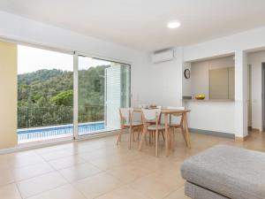 ein Wohnzimmer mit einem Tisch und Stühlen sowie einem großen Fenster in der Unterkunft Holiday Home El Moli-1 by Interhome in Tossa de Mar + 18 Fotos
