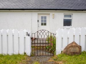 a white fence in front of a white house at Holiday Home Orral Cottage by Interhome in Kilmuir