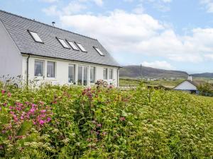 a white house with a field of flowers at Holiday Home Orral Cottage by Interhome in Kilmuir