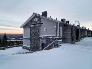 una cabaña de madera en la nieve en invierno en Näköalahuoneisto 420, en Syöte