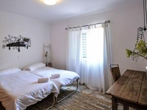 a bedroom with a bed and a table and a window at Holiday Home Romanzeira by Interhome in Moncarapacho