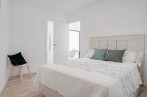 a white bedroom with a white bed and a chair at New Apartment With Stunning Views in Mijas