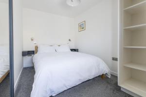 a bedroom with a white bed and shelves at Pitts Cottage Annexe in Bladon