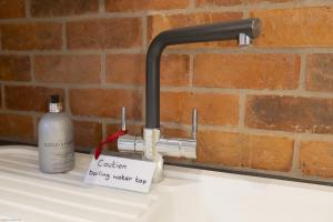 a water tap with a bottle of soap on a sink at Pitts Cottage Annexe in Bladon +13 photos