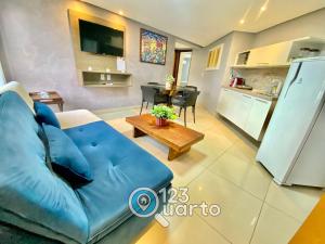 a living room with a blue couch and a kitchen at Gold Flat Cabo Branco By 123Quarto Hospedagem in Tambaú