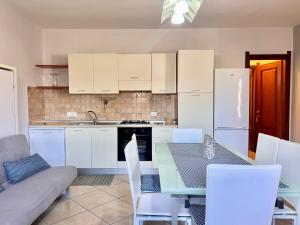 a kitchen with white cabinets and a table with chairs at Dalia House - Key to Villas in Valledoria
