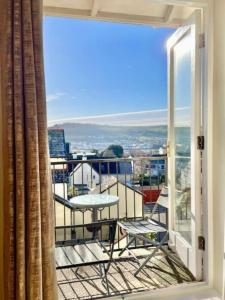 ein Balkon mit Tisch und Stühlen und einem Fenster in der Unterkunft Kanangra, 2 bedroom apartment in Teignmouth in Teignmouth + 14 Fotos