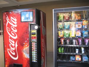 a cocacola soda vending machine next to a refrigerator at The Garden Villas Hotel in Valdosta