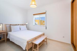 a white bedroom with a bed and a window at TAC - Serenity Manta Rota in Vila Nova De Cacela