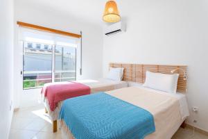 two beds in a room with a window at TAC - Serenity Manta Rota in Vila Nova De Cacela