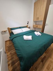 Un dormitorio con una cama verde con toallas. en AB Apartman Zlatibor, en Zlatibor