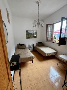 a bedroom with two beds and a table and windows at Casa Chana y Domingo- Refugio con historia y vistas en Agulo in Agulo