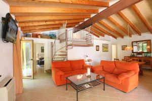 a living room with orange furniture and a spiral staircase at Ca Na Barbara in Santanyi
